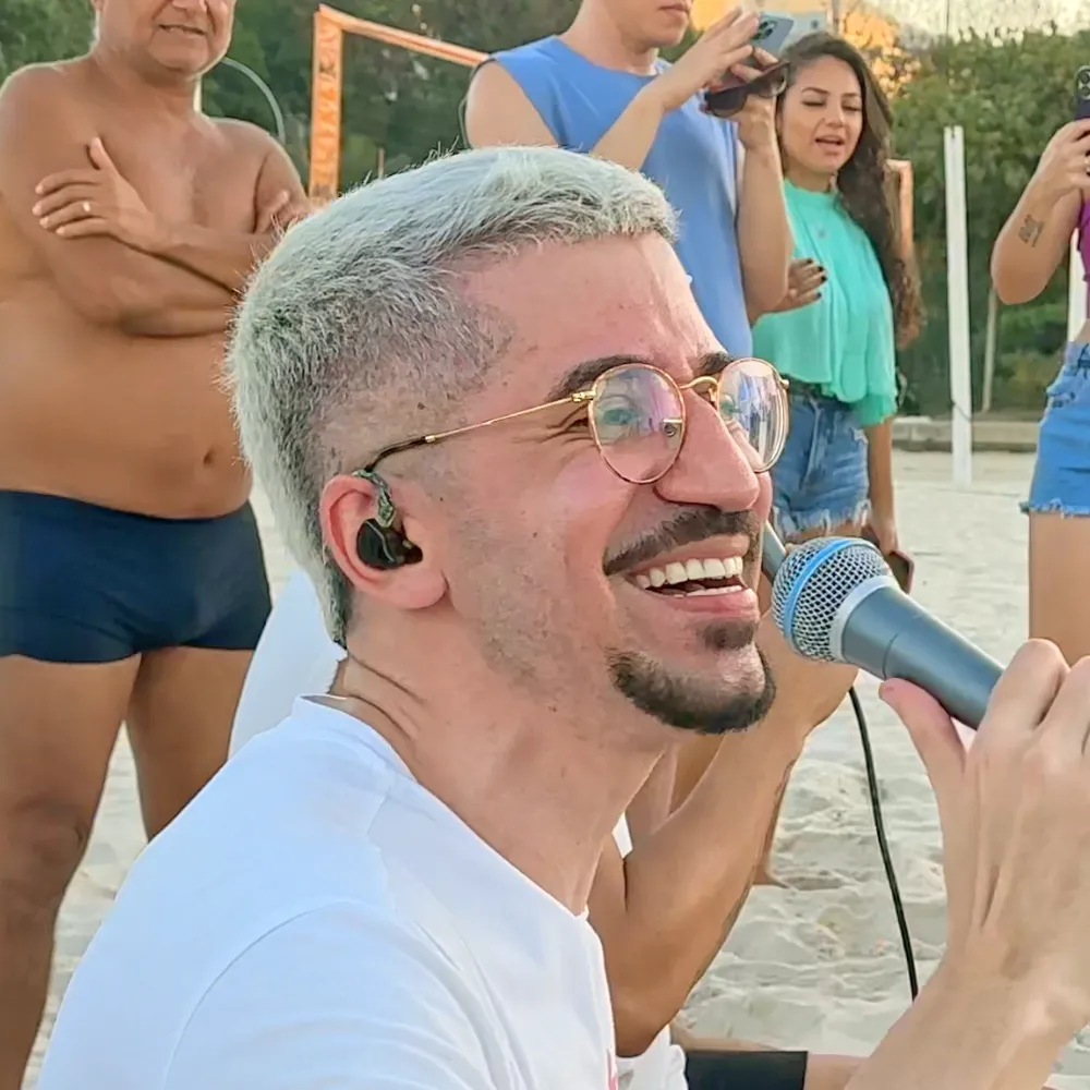 Foto quadrada do Leleco cantando na praia
